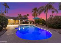 Inviting backyard pool with lounge chairs, umbrellas, and lush landscaping creates a perfect private oasis at 3531 E Becker Ln, Phoenix, AZ 85028