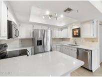 White kitchen features stainless steel appliances, ample countertop space, and natural light at 4200 N Miller Rd # 220, Scottsdale, AZ 85251