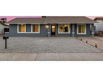 Charming single-story home featuring stylish gray paint, white trim windows, and a low-maintenance rock front yard at 7906 W Catalina Dr, Phoenix, AZ 85033