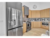 Modern kitchen with stainless steel refrigerator, wooden cabinets, dark range hood and backsplash at 8245 E Bell Rd # 201, Scottsdale, AZ 85260