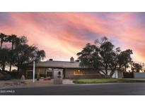 Charming single-story brick home featuring desert landscaping and mature trees against a vibrant sunset sky at 11420 N 50Th St, Scottsdale, AZ 85254