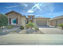 Charming single-story home featuring a stone facade, desert landscaping, and a paver driveway at 26439 W Covey Ln, Buckeye, AZ 85396