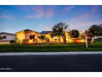 Inviting single-story home with lush landscaping, enhanced by warm exterior lighting at dusk at 3531 E Norwood Cir, Mesa, AZ 85213