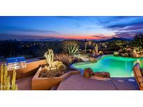 Desert landscaping surrounds the backyard pool with city views at dusk at 41688 N 111Th Pl, Scottsdale, AZ 85262