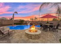 Inviting backyard with a stone fire pit, a pristine pool with a waterfall, and comfortable seating, perfect for outdoor relaxation at 11965 W Monte Vista Rd, Avondale, AZ 85392