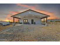 Charming property featuring a large, covered patio with ceiling fans and desert landscaping at sunset at 4188 N Plaza Dr, Apache Junction, AZ 85120