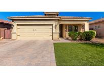 Charming single-story home featuring a two-car garage, brick driveway, and well-manicured lawn at 828 W Leadwood Ave, San Tan Valley, AZ 85140