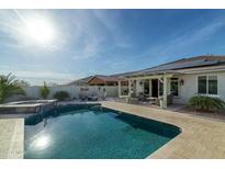 Inviting backyard pool with spa, lush landscaping, covered patio, and cozy seating for outdoor gatherings at 12031 E Chevelon Trl, Gold Canyon, AZ 85118