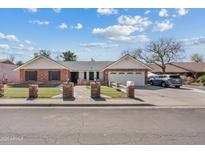 Charming single-story brick home featuring mature landscaping, a two-car garage, and inviting curb appeal at 1331 E Bates St, Mesa, AZ 85203