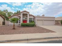 Charming single-story home features a red front door, desert landscaping, and a three-car garage at 1915 E Citation Ln, Tempe, AZ 85284