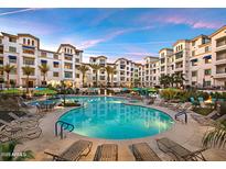 Beautiful community pool featuring lounge chairs and palm trees and beautiful apartment buildings at 2511 W Queen Creek Rd # 307, Chandler, AZ 85248