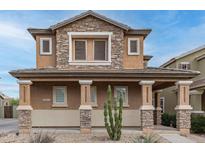 Inviting two-story home boasts a charming stone facade and covered porch, blending warmth with architectural appeal at 34913 N 30Th Dr, Phoenix, AZ 85086