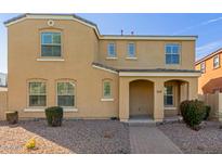 Tan two-story home with a covered porch entry, desert landscaping, and brick paver walkway at 3555 E Erie St, Gilbert, AZ 85295
