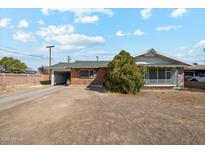 Charming single-story home with a brick facade, green roof, spacious front yard and attached garage at 4020 W Tuckey Ln, Phoenix, AZ 85019