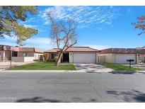 Charming single-story home with a tile roof, green lawn, and a two-car garage at 12215 S Potomac St, Phoenix, AZ 85044