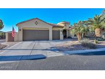 Attractive tan home featuring a two car garage, a circular tower feature, and desert landscaping at 16409 W Alvarado Dr, Goodyear, AZ 85395