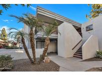 Inviting condo exterior with palm trees, stairs to upper units, and a clean, modern aesthetic under a clear blue sky at 17211 N 35Th Ave, Phoenix, AZ 85053