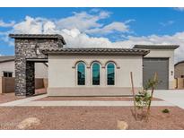 Charming home exterior featuring a stone accent wall, arched windows, and well-maintained landscaping at 17312 W Royal Palm Rd, Waddell, AZ 85355