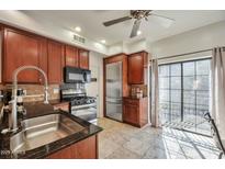 Well-equipped kitchen features stainless steel appliances, granite counters, and beautiful wooden cabinets at 3428 E Lance Ln, Phoenix, AZ 85018