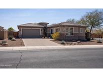 Inviting single-story home featuring a brick driveway, stone accents, and a two-car garage at 10657 E Evergreen St, Mesa, AZ 85207