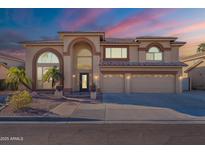 A grand home with a three-car garage and arched windows, complemented by desert landscaping and palm trees at 12925 W Llano Dr, Litchfield Park, AZ 85340