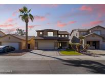 Two-story home featuring a spacious driveway, desert landscaping and a palm tree at 14309 W Weldon Ave, Goodyear, AZ 85395