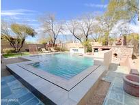 Inviting backyard pool with stone accents, outdoor fireplace, and a serene waterfall feature at 3912 E Williams Dr, Phoenix, AZ 85050