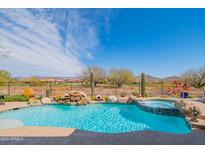 Backyard pool with waterfall feature and jacuzzi offers a tranquil outdoor space with desert views at 40607 N Candlewyck Ln, Phoenix, AZ 85086