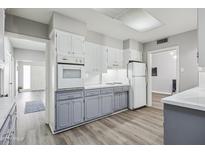 Traditional-style kitchen with white cabinets and oven range, grey lower cabinets, and wood-look flooring at 713 E Eason Ave, Buckeye, AZ 85326