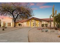 Inviting single-story home featuring desert landscaping, covered entryway, and attached garage at 8254 E Juan Tabo Rd, Scottsdale, AZ 85255