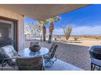 Outdoor patio area with a table and chairs with gravel, plants, and swimming pool in the background at 100 N Vulture Mine Rd # 103, Wickenburg, AZ 85390