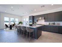 Modern kitchen with dark cabinets, an island with seating, stainless steel appliances, and tile backsplash at 24066 S 218Th Pl, Queen Creek, AZ 85142