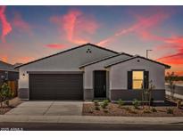 Charming single-story home featuring stucco, a two-car garage, and a desert-landscaped front yard under a colorful sunset sky at 3864 N Camden Dr, Florence, AZ 85132