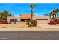 Charming single-story home featuring a desert landscape, red flowers, and a vibrant blue sky at 5024 E Le Marche Ave, Scottsdale, AZ 85254