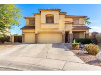 Two-story tan stucco home with a three-car garage and mature landscaping at 19221 N Toya St, Maricopa, AZ 85138
