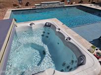 Inviting backyard features a sparkling pool and a relaxing hot tub, perfect for outdoor enjoyment and leisure at 21432 W Minnezona Ave, Buckeye, AZ 85396