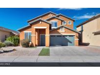 Two-story tan home with a gray door, matching gray garage door, and desert landscaping at 44440 W Palmen Dr, Maricopa, AZ 85138