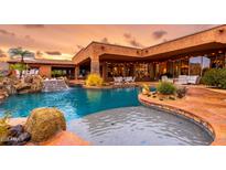 Stunning pool with rock waterfall features and lush landscaping, perfect for outdoor relaxation and entertainment at 12160 E Whispering Wind Dr, Scottsdale, AZ 85255