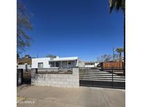 The home has a xeriscaped front yard and a dark gray horizontal metal fence around the perimeter at 1414 E Moreland St, Phoenix, AZ 85006