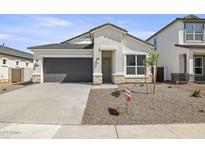 Charming single-Gathering home features a gray garage door, stone accents, and low-maintenance landscaping at 17819 W Mission Ln, Waddell, AZ 85355