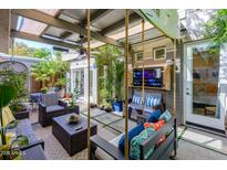 Inviting outdoor living space with comfortable seating, a TV, tropical plants, and a unique hanging swing at 5205 N 8Th Pl, Phoenix, AZ 85014