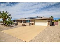 Single story home featuring desert landscaping, solar panels and a large driveway at 12530 W Skylark Dr, Sun City West, AZ 85375