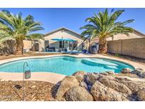 Inviting backyard pool features rock accents, two palm trees, and a bright blue umbrella at 22531 W Yavapai St, Buckeye, AZ 85326