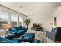 Bright living room with modern furnishings, large windows, and neutral color palette and a beautiful blue couch at 2425 W Bronco Butte Trl # 2024, Phoenix, AZ 85085