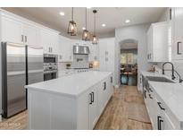 Bright kitchen with white cabinetry, stainless steel appliances, quartz countertops and pendant lighting at 30259 N 125Th Ln, Peoria, AZ 85383