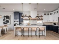 Stunning kitchen with a large waterfall island, stylish pendant lights, and modern two-tone cabinetry at 3628 E Clarendon Ave, Phoenix, AZ 85018