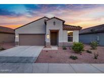 Charming single-story home with a well-maintained front yard and attached two-car garage at sunset at 42195 W Lavender Dr, Maricopa, AZ 85138