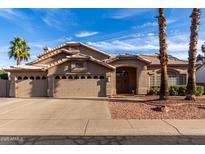 Charming single-story home featuring a three-car garage, desert landscaping, and a tile roof at 21041 N 61St Dr, Glendale, AZ 85308