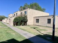 A tan apartment complex with well-maintained landscaping on a sunny day at 6841 W Devonshire Ave, Phoenix, AZ 85033