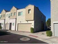 Modern townhouse with a two-car garage and landscaped front, under a clear blue sky at 8330 N 22Nd Ln, Phoenix, AZ 85021